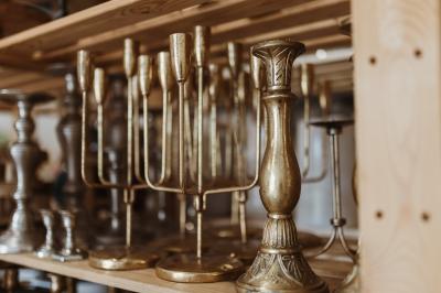Bougeoirs en laiton et en métal argenté alignés sur des étagères en bois dans un espace de rangement.