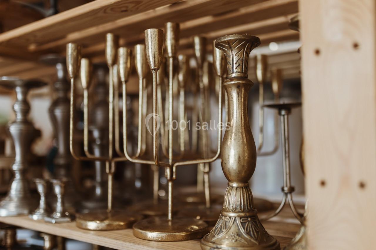 Bougeoirs en laiton et en métal argenté alignés sur des étagères en bois dans un espace de rangement.