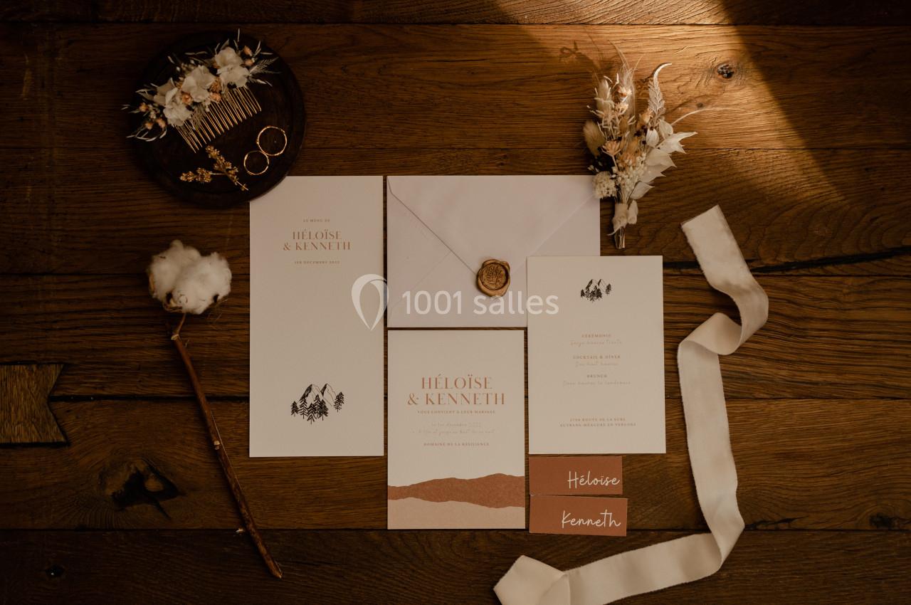 Papeterie de mariage élégante sur une table en bois, avec enveloppe scellée, cartes et accessoires décoratifs.