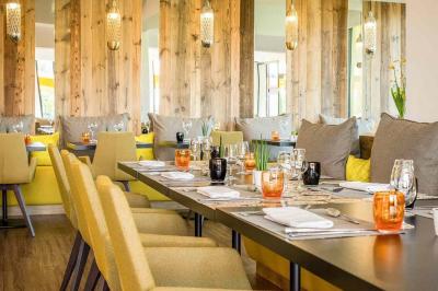 Chambre d'hôtel avec lit double, bureau en bois, lampe suspendue, fenêtre et décoration murale rouge et beige.