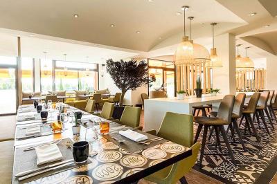 Chambre d'hôtel avec lit double, bureau en bois, lampe suspendue, fenêtre et décoration murale rouge et beige.