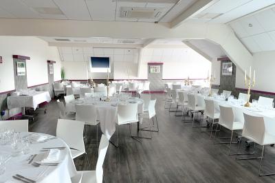 Chambre d'hôtel avec lit double, bureau en bois, lampe suspendue, fenêtre et décoration murale rouge et beige.