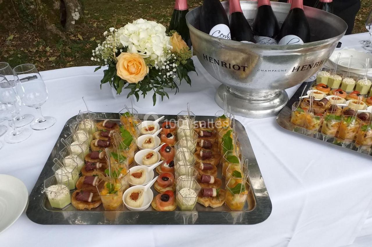 Plateaux de verrines et amuse-bouches disposés sur une table avec des bouteilles de champagne dans un seau.