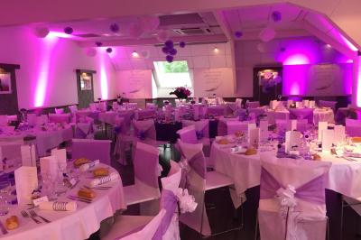 Chambre d'hôtel avec lit double, bureau en bois, lampe suspendue, fenêtre et décoration murale rouge et beige.