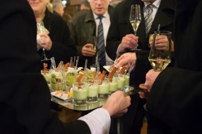 Chambre d'hôtel avec lit double, bureau en bois, lampe suspendue, fenêtre et décoration murale rouge et beige.