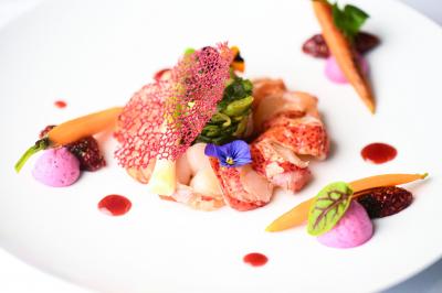 Chambre d'hôtel avec lit double, bureau en bois, lampe suspendue, fenêtre et décoration murale rouge et beige.