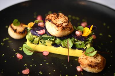 Chambre d'hôtel avec lit double, bureau en bois, lampe suspendue, fenêtre et décoration murale rouge et beige.