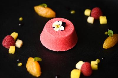 Chambre d'hôtel avec lit double, bureau en bois, lampe suspendue, fenêtre et décoration murale rouge et beige.