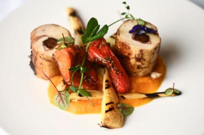 Chambre d'hôtel avec lit double, bureau en bois, lampe suspendue, fenêtre et décoration murale rouge et beige.