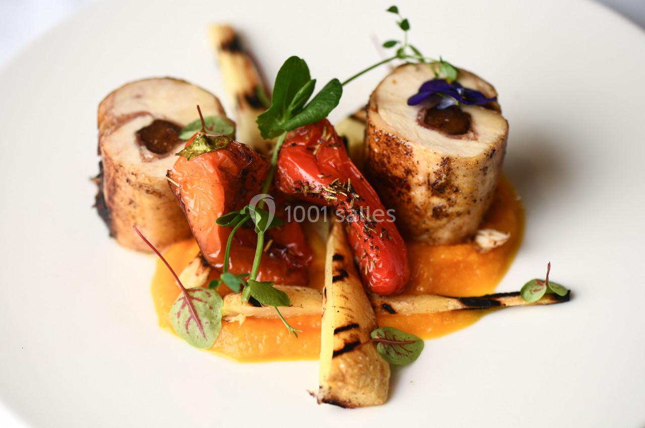 Assiette gastronomique avec roulés de volaille, légumes grillés, purée orange et herbes fraîches.