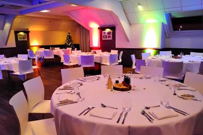 Chambre d'hôtel avec lit double, bureau en bois, lampe suspendue, fenêtre et décoration murale rouge et beige.