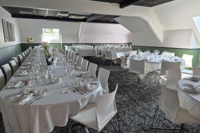 Chambre d'hôtel avec lit double, bureau en bois, lampe suspendue, fenêtre et décoration murale rouge et beige.