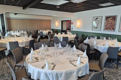 Chambre d'hôtel avec lit double, bureau en bois, lampe suspendue, fenêtre et décoration murale rouge et beige.