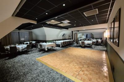 Chambre d'hôtel avec lit double, bureau en bois, lampe suspendue, fenêtre et décoration murale rouge et beige.