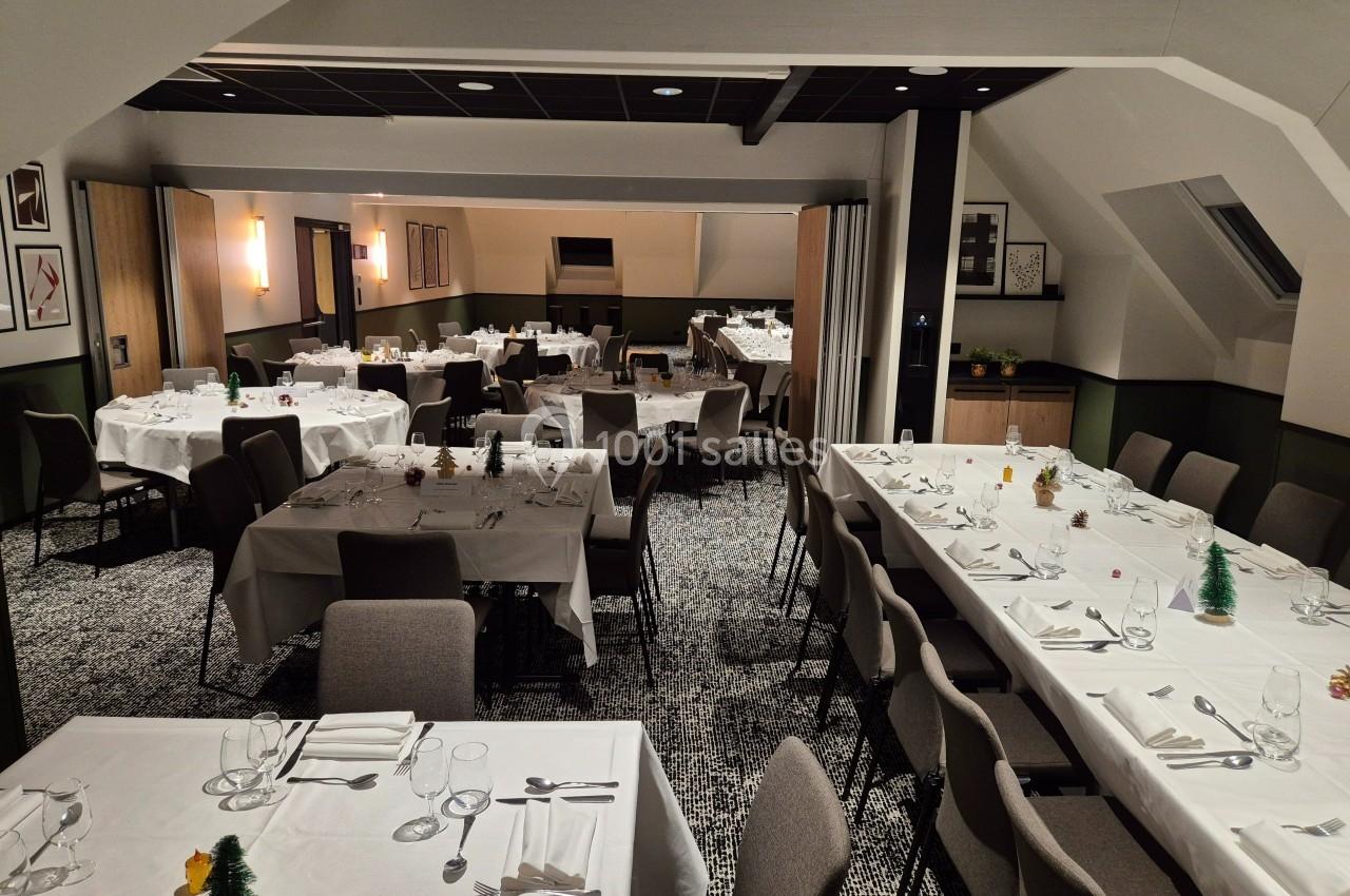 Salle de réception élégamment aménagée avec des tables dressées, nappes blanches et décorations minimalistes.