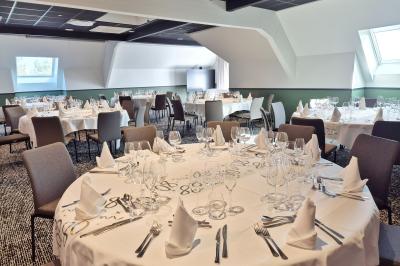 Chambre d'hôtel avec lit double, bureau en bois, lampe suspendue, fenêtre et décoration murale rouge et beige.