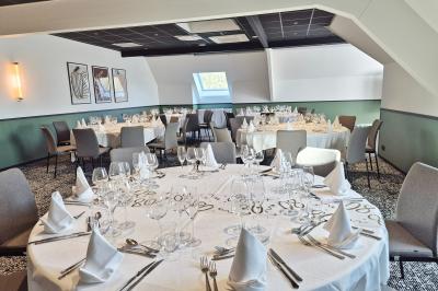 Chambre d'hôtel avec lit double, bureau en bois, lampe suspendue, fenêtre et décoration murale rouge et beige.