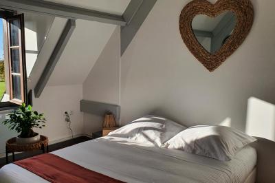 Bâtiments en colombages et en briques avec toiture en ardoise, entourés de végétation sous un ciel partiellement nuageux.