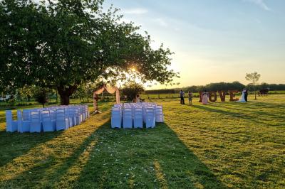 Bâtiments en colombages et en briques avec toiture en ardoise, entourés de végétation sous un ciel partiellement nuageux.