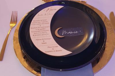 Bâtiments en colombages et en briques avec toiture en ardoise, entourés de végétation sous un ciel partiellement nuageux.