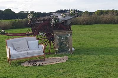 Bâtiments en colombages et en briques avec toiture en ardoise, entourés de végétation sous un ciel partiellement nuageux.