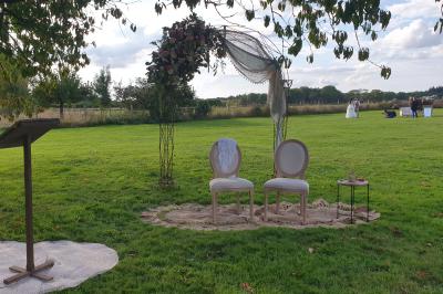 Bâtiments en colombages et en briques avec toiture en ardoise, entourés de végétation sous un ciel partiellement nuageux.