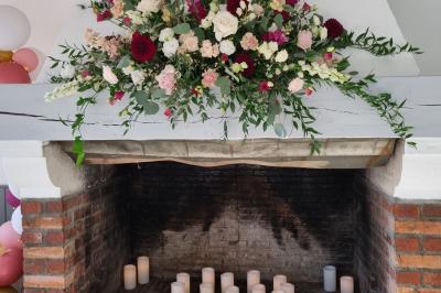 Bâtiments en colombages et en briques avec toiture en ardoise, entourés de végétation sous un ciel partiellement nuageux.