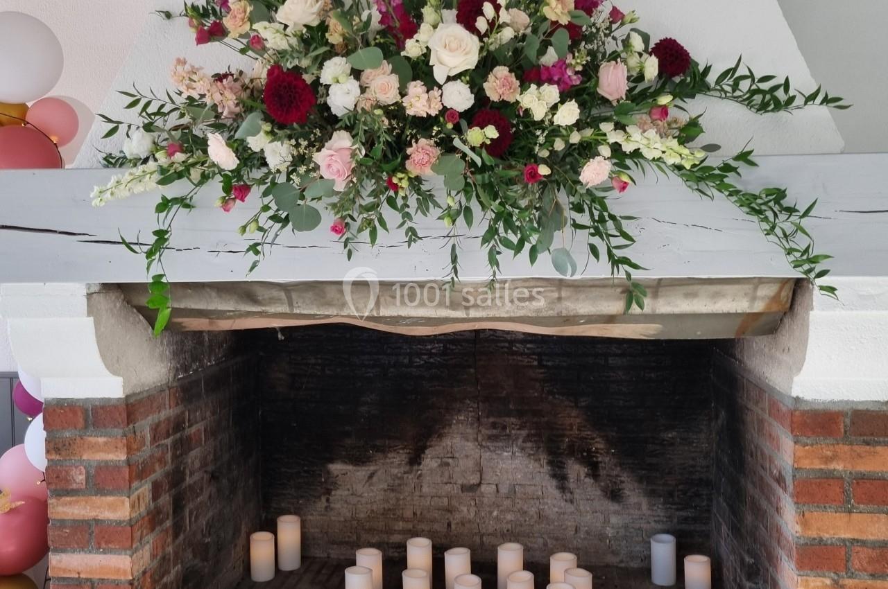 Cheminée en briques décorée de fleurs colorées et de bougies blanches disposées à l'intérieur.