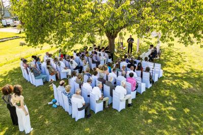 Bâtiments en colombages et en briques avec toiture en ardoise, entourés de végétation sous un ciel partiellement nuageux.