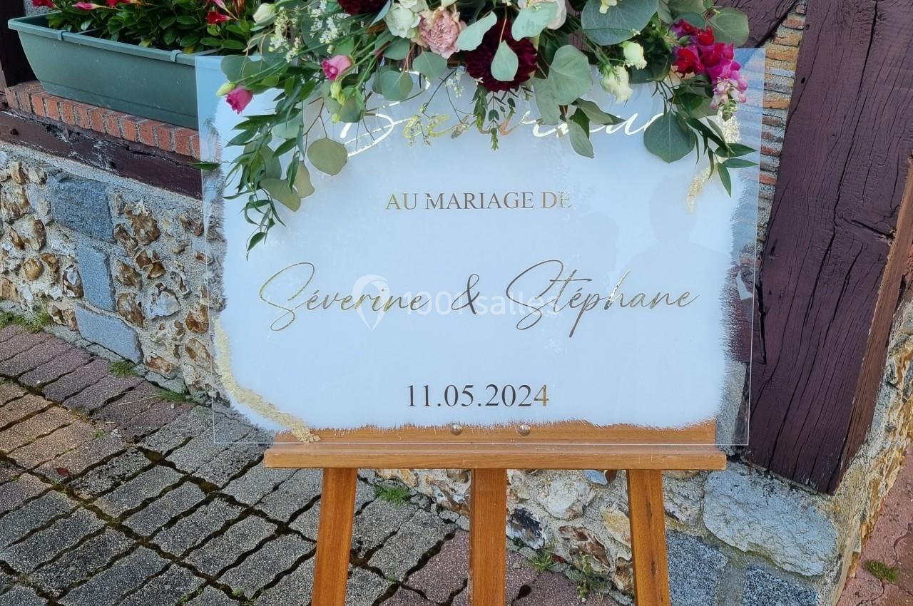 Panneau de mariage sur chevalet en bois, décoré de fleurs colorées, avec les prénoms des mariés et la date du 11 mai 2024.
