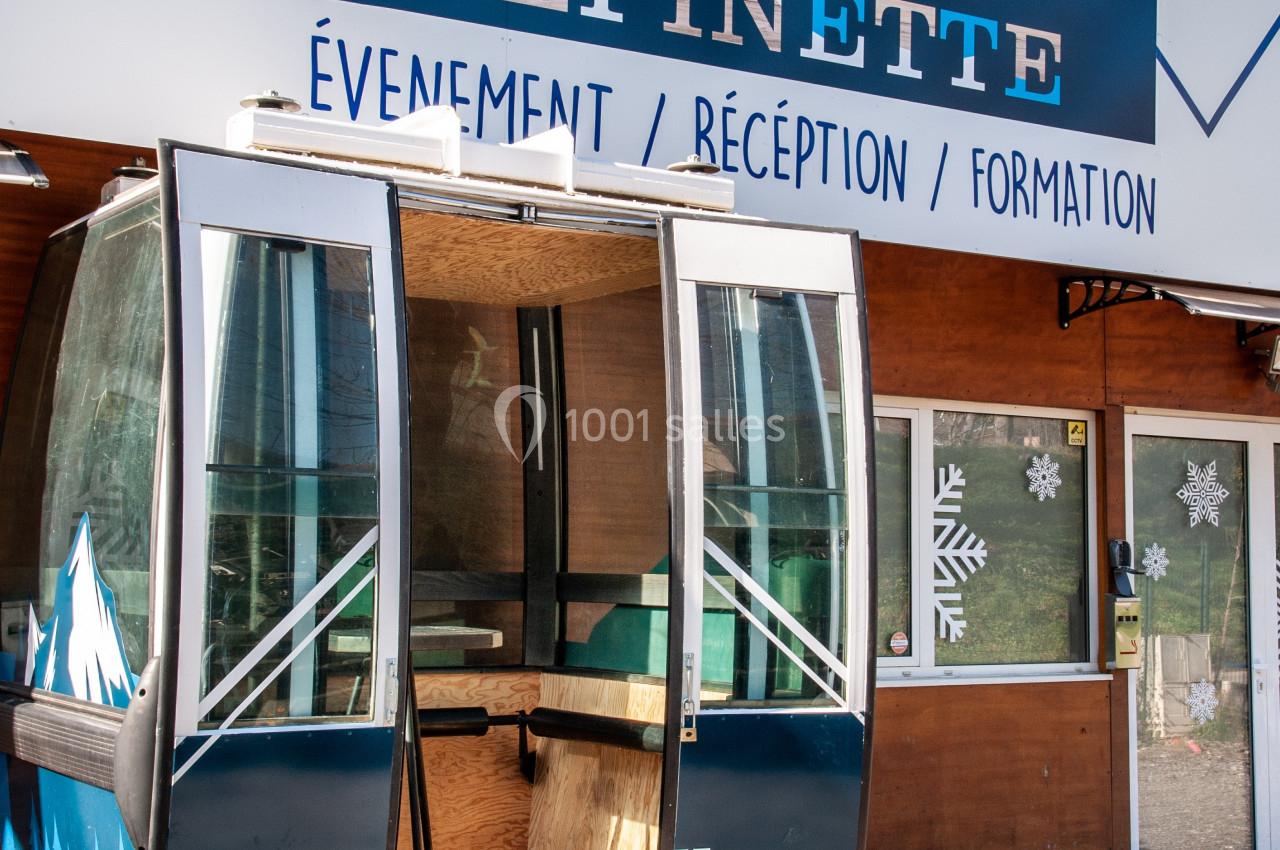 Une ancienne cabine de télécabine transformée en espace d'accueil devant un bâtiment nommé ’Salle Epinette’.