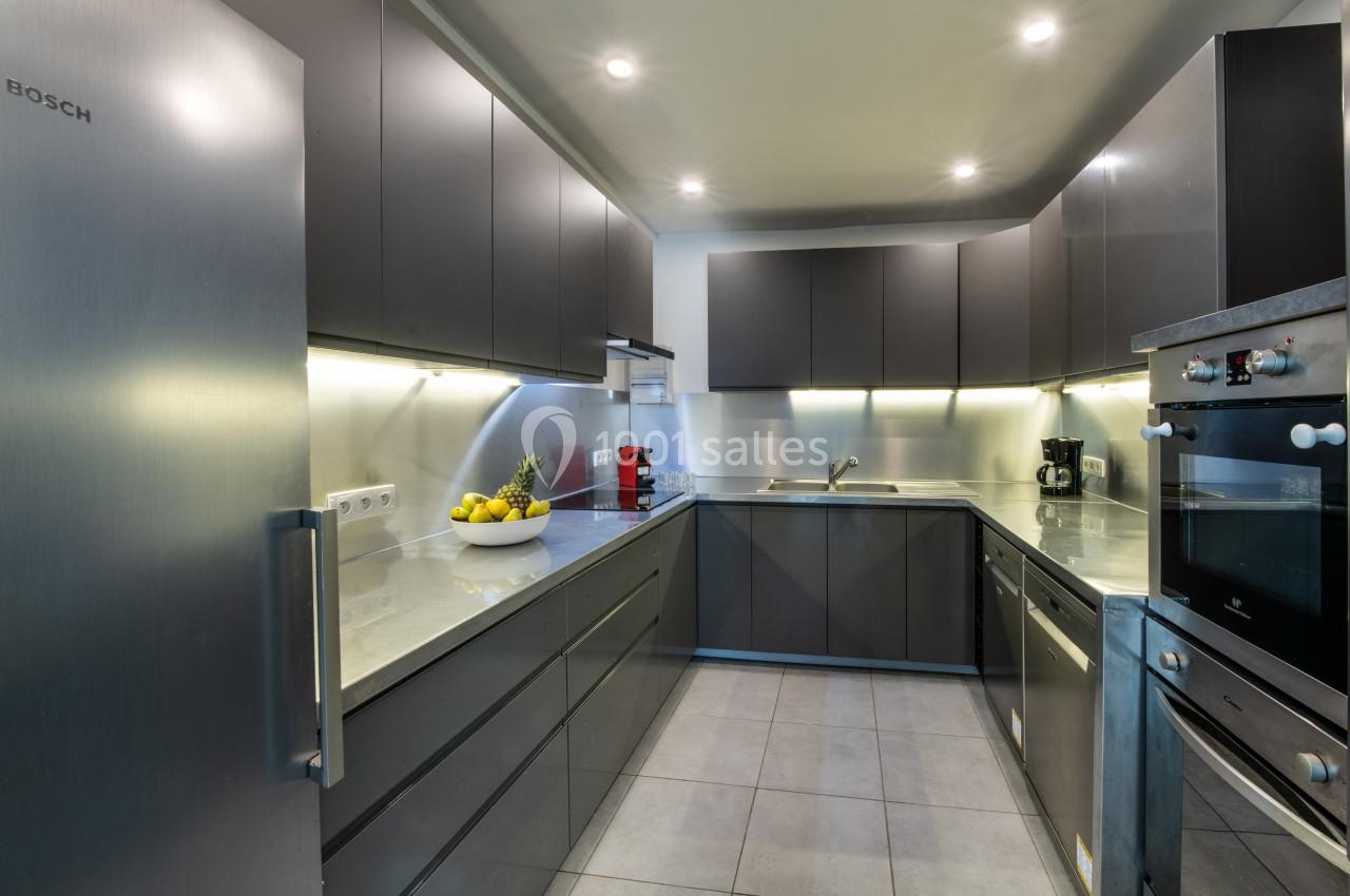 Cuisine moderne avec meubles gris, plan de travail clair, électroménagers intégrés et éclairage encastré.