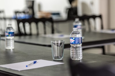 Table avec cafetières, tasses bleues empilées et panier de viennoiseries, dans un espace de pause.