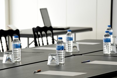 Table avec cafetières, tasses bleues empilées et panier de viennoiseries, dans un espace de pause.