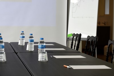Table avec cafetières, tasses bleues empilées et panier de viennoiseries, dans un espace de pause.