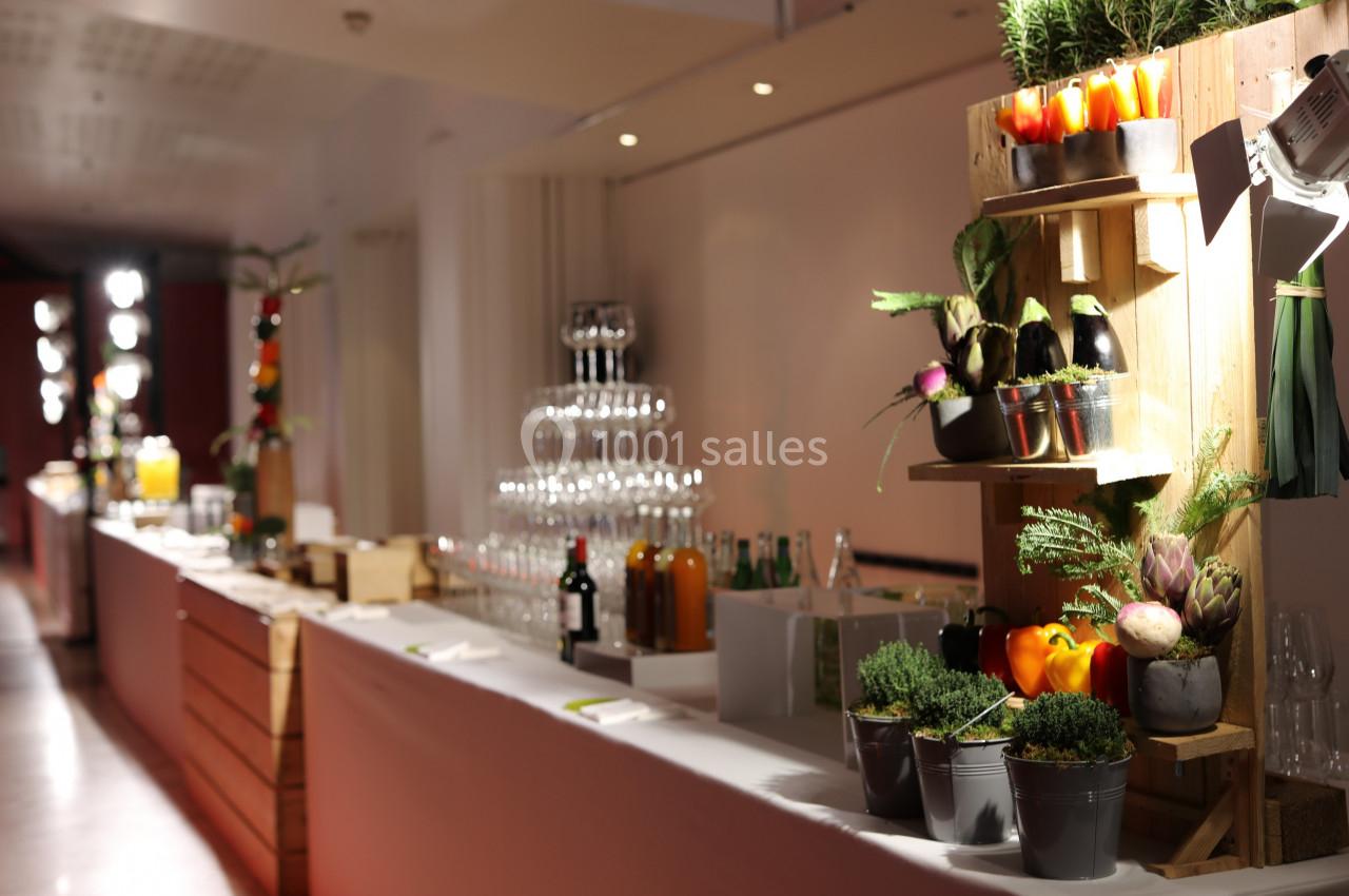 Table de buffet élégante avec verres empilés, boissons et décorations végétales sur des étagères en bois.