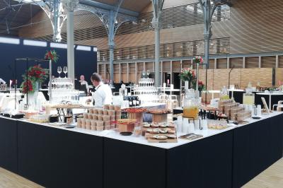 Buffet dressé dans une grande salle avec structure métallique, proposant boissons, viennoiseries et plats variés.