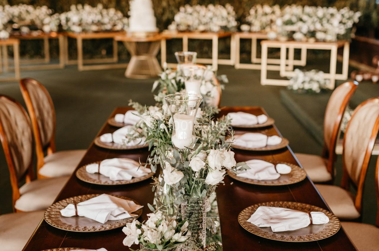 Table élégamment dressée avec des assiettes, serviettes pliées et décorations florales dans une salle ornée de guirlandes…