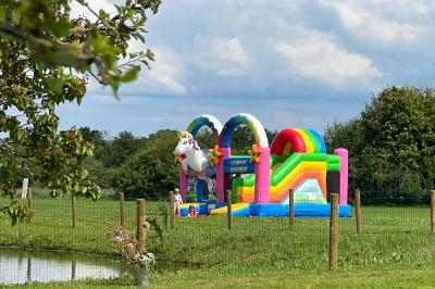 Chambre lumineuse sous les combles avec quatre lits simples, poutres apparentes et fenêtre de toit.