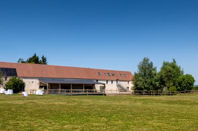 Chambre lumineuse sous les combles avec quatre lits simples, poutres apparentes et fenêtre de toit.