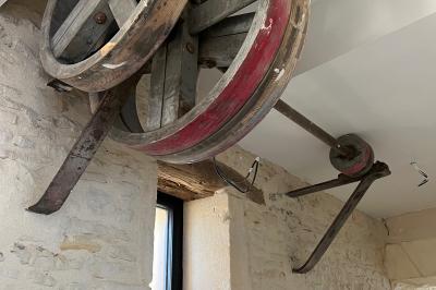 Chambre lumineuse sous les combles avec quatre lits simples, poutres apparentes et fenêtre de toit.