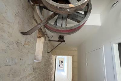 Chambre lumineuse sous les combles avec quatre lits simples, poutres apparentes et fenêtre de toit.