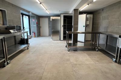 Chambre lumineuse sous les combles avec quatre lits simples, poutres apparentes et fenêtre de toit.