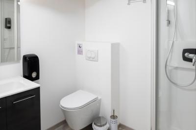 Chambre lumineuse sous les combles avec quatre lits simples, poutres apparentes et fenêtre de toit.