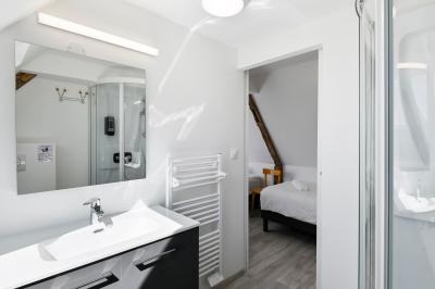 Chambre lumineuse sous les combles avec quatre lits simples, poutres apparentes et fenêtre de toit.
