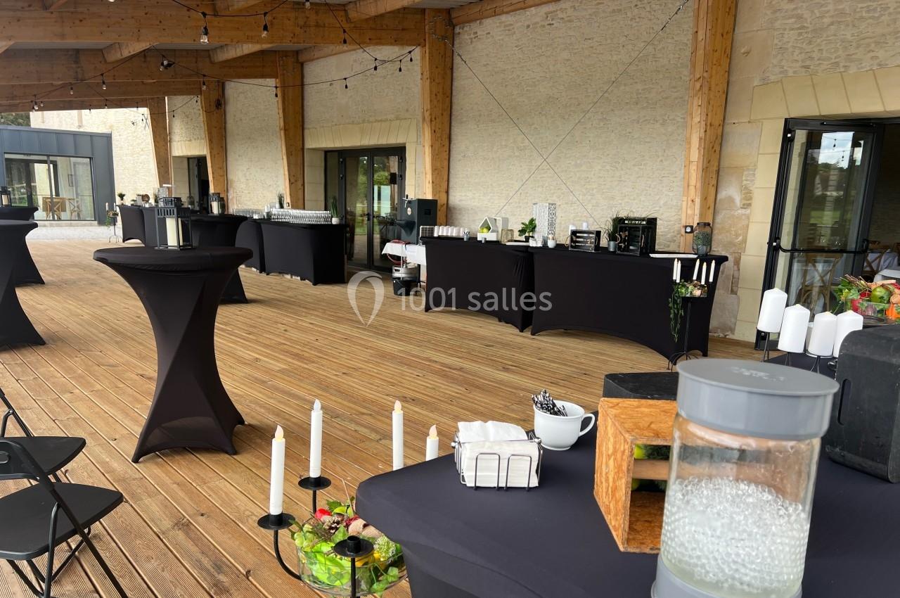 Terrasse en bois aménagée pour un événement avec tables hautes, nappes noires et décorations élégantes.