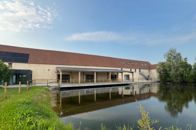 Chambre lumineuse sous les combles avec quatre lits simples, poutres apparentes et fenêtre de toit.