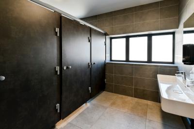 Chambre lumineuse sous les combles avec quatre lits simples, poutres apparentes et fenêtre de toit.