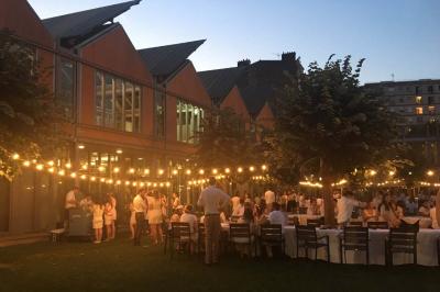 Un technicien supervise un enregistrement en studio, avec trois personnes chantant derrière une vitre insonorisée.