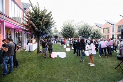 Un technicien supervise un enregistrement en studio, avec trois personnes chantant derrière une vitre insonorisée.